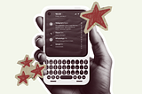 A hand holding a cellphone with a physical keyboard. Decorated with red cutout stars.