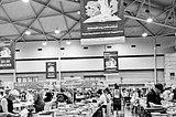 A black and white photo of Brisbane Lifeline Bookfest featuring long tables of books for sale and shoppers browsing.