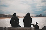 The back of two figures looking out to sea