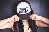 A woman wearing a cap with the message “Sorry mom.”