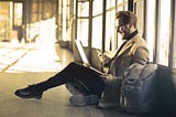 Business traveller sitting on ground with laptop