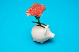 A piggybank with a flower in it.