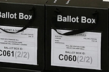 Ballot boxes in black with British voting authorities on them.