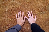 Two hands with wedding rings over a heart.