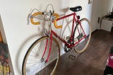 A vintage red bike with gold taped, curly handlebars