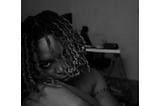 A black and white picture of the author-Keyukemi, staring at the camera intently with a straight face, her hair partially covering her eyes.