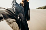 Woman in black walking on a beach