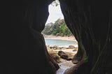A tunnel looking out to a beach. Your path begins within you.