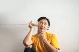 Man listening curiously to string and cup “telephone”