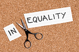 Photo showing the word “inequality” written on a piece of paper and cut between the N and E