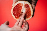 hand fingering a grapefruit cut in half