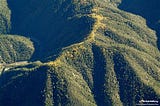 Photo of a mountain ridge. Green on both sides and brown on the ridge top path.