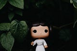 Funko Pop toy of Princess Leia in front of green leaves.