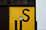 the word “us” painted on a door so that the top of the U and the bottom of the S are holding hands