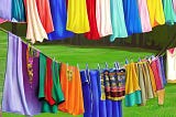 Image created by author using Dream.ai of colorful laundry hanging outside on a close line to dry.