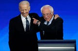 Former US vice president Joe Biden, left, embraces Sen. Bernie Sanders during a Democratic presidential primary debate