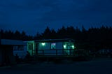 An illuminated trailer park store at night.