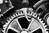 Photo from the movie Modern Times of Charlie Chaplin adjusting a large mechanical cog.