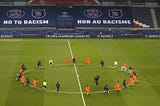 Photo by Xaiver Laine, AP Istanbul Basaksehir and PSG players kneel on the pitch against racism before the match.