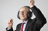 An elderly man listening to music on headphones and he is happy