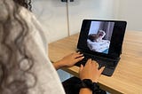 A woman looking at picture of a cat yawning on her computer.