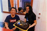 My father and I on my 28th birthday in 2022. We’re both smiling. I’m holding a chocolate cake with “Happy Birthday, Jonnah” written on it.