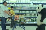 A panda confronts a father and son in the dairy aisle of a grocery store