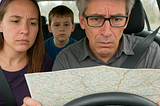 A lost family in car looking at map for directions in the days before cell phones, Mapquest and in-car navigation systems.