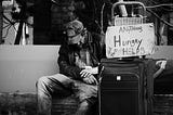 Homeless, poor, hungry man with sign asking for help with food or money.