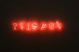 Photo of red neon text against a dark backdrop. The text is a series of seven symbols.