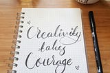A coiled notebook with words ‘Creativity takes courage’ written in cursive