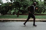 A man jogs along a quiet park road, surrounded by lush greenery, embodying dedication to fitness, outdoor exercise, and a healthy lifestyle. Reflecting the perspective of Ramneek Bhogal on why men over 40 should rethink their wellness routine.