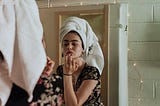 an image of a woman putting make-up in front of a mirror.