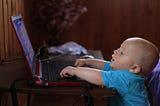 Toddler reaches to type on an open laptop