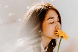 Young woman smells flowers with eyes closed, enraptured