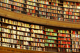 Estante com muitos livros e um senhor observando. Imagem para representar a quantidade enorme de informações que temos.