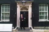 Neil Mapes, the author, dressed in a suit and tie outside the front door of number ten downing street.