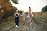 an-older-woman-with-a-younger-woman-and-a-child-running-down-a-path