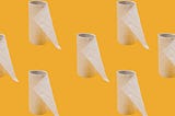 Rolls of almost used up toilet paper spaced in front of a orange background