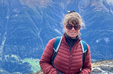A smiling woman stands in front of the mountains