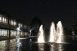 A night shot of the fountain outside The National Archives, with a crescent moon and Venus above