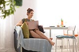 A woman relaxing on the sofa at home working on a laptop