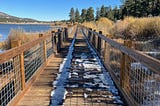 A scenic hiking trail surrounded by towering pine trees near Big Bear Lake, California, with sunlight filtering through the forest, symbolizing personal growth, self-reflection, and the balance between stability and evolution