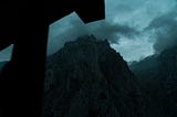 moody photo of mountains with clouds and a dark shadow of a house awning