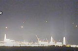 In the night sky, several UFO balls of light hover over the brightly lit Fukushima Daiichi nuclear power station, immediately after the large earthquake in 2011