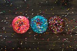 Phot of three donuts with sprinkles