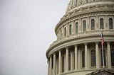 Photo of a building dome with American flag in front.