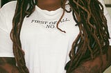 Close-up of defiant Black woman with her hands crossed in front of her wearing white tee with the words: FIRST OF ALL, NO.