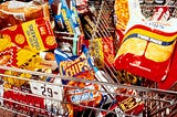 IMAGE: A shoipping cart filled with all sorts of ultra-processed foods and snacks