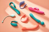Various sex toys in pastel colours against a peach background